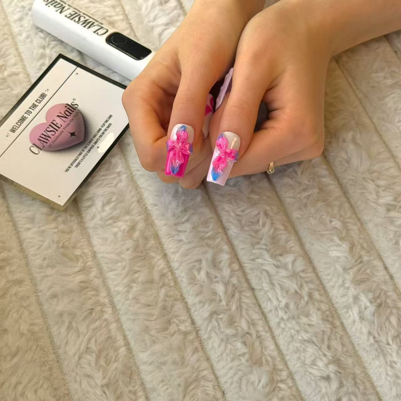 CLAWSIE Nails Viola medium square press-on nails thumb close-up, with pink and purple 3D flower decorations.